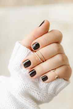 手黑色的修指甲环指骨短指甲白色毛衣光背景概念时尚的温暖的冬天