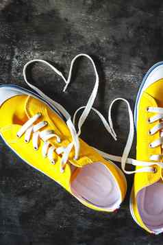 黄橙色的运动鞋难看的东西混凝土黑暗背景数字心鞋带视图特写镜头概念