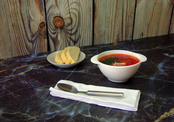 传统的俄罗斯汤罗宋汤酸奶油草本植物站表格块面包板餐巾勺子特写镜头