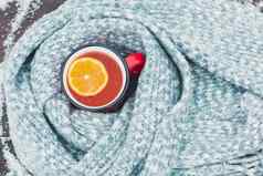 红色的涂漆的杯热茶柠檬包装针织围巾雪木表格前维乌平躺