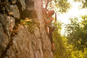 美丽的女人攀爬岩石多雾的日落山冒险极端的体育运动概念