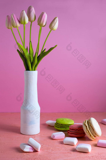 蛋白杏仁饼小白色粉红色的棉花糖分散苍白的粉红色的背景花瓶郁金香的地方文本