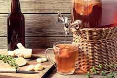 新鲜的自制的红茶菌发酵茶喝Jar水龙头杯瓶木背景