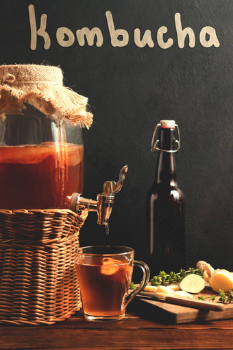 新鲜的自制的红茶菌发酵茶喝Jar水龙头杯瓶黑色的背景垂直图像