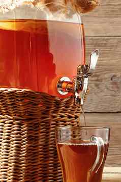新鲜的自制的红茶菌发酵茶喝Jar水龙头杯木背景垂直图像