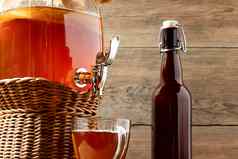 新鲜的自制的红茶菌发酵茶喝Jar水龙头杯瓶木背景