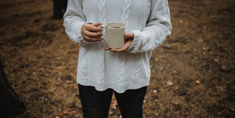 年轻的女人白色毛衣持有杯茶咖啡背景黄色的秋天叶子温暖的秋天大气软焦点复制空间
