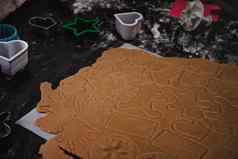 减少姜饼饼干形式圣诞节树明星男人。心生面团羊皮纸烘焙纸黑暗背景前视图保存空间
