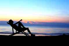 躺椅男人。海滩日落