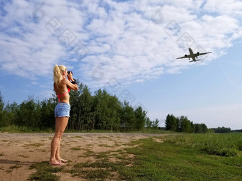 金发女郎女孩长头发需要图片飞机飞行多云的天空背景