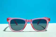 粉红色的明亮的太阳镜柔和的蓝色的背景夏天时间