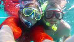 快乐年轻的夫妇采取自拍水下戴面具的浮潜肖像