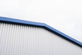 金属波纹表建筑蓝色的金属角落白色铝金属波纹屋顶墙表多云的天空背景工厂工业建筑