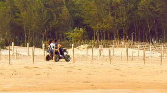 度蜜月夫妇骑机动化的三轮车有轮子的三轮车摩托车沿海路沙子海海滩夏天日落旅行旅游假期假期背景概念