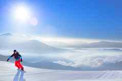 滑雪骑红色的滑雪板坡山明亮的太阳滑雪冬天体育概念
