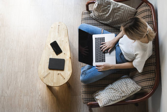 女人移动PC坐着沙发研究工作在线自由使用女人女孩工作笔记本坐着沙发上电话智能手机ereader表格