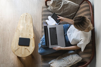 女人移动PC坐着沙发智能手机研究工作在线自由使用女孩工作笔记本坐着沙发上电话ereader表格