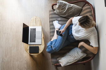 女人移动PC坐着沙发智能手机研究工作在线自由使用女孩工作笔记本坐着沙发上电话ereader表格