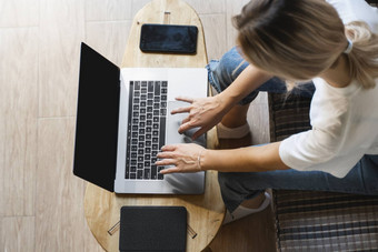 女人坐着沙发移动PC木表格研究工作在线自由使用女孩工作笔记本坐着沙发上电话ereader表格