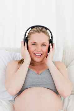 可爱的怀孕了女人听音乐床上