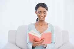 微笑有吸引力的女人坐着舒适的沙发阅读书