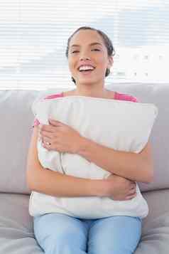 微笑女人坐着沙发拥抱枕头