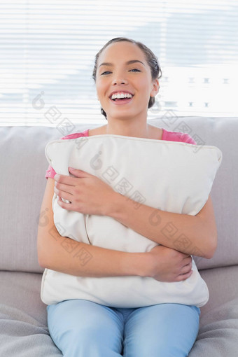 微笑女人坐着沙发拥抱枕头