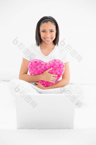 微笑年轻的黑暗头发的模型拥抱枕头移动PC