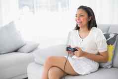 笑年轻的黑暗头发的女人白色衣服玩视频游戏