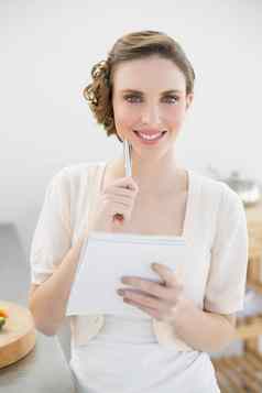 快乐的女人思考写作购物列表厨房