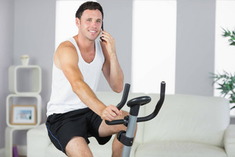 快乐的运动男人。锻炼自行车打电话
