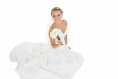 快乐的年轻的新娘坐着地板上显示花束