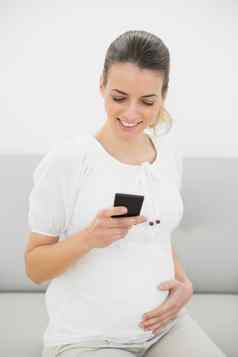 华丽的怀孕了女人消息传递智能手机持有肚子