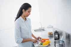 漂亮的黑色的头发的女人准备餐明亮的厨房