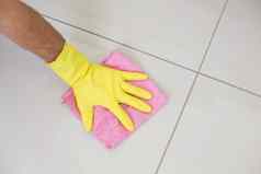 黄色的戴着手套手清洁破布擦拭地板上