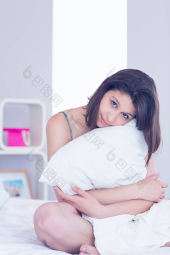 美丽的浅黑肤色的女人拥抱枕头
