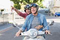 快乐成熟的夫妇骑踏板车城市