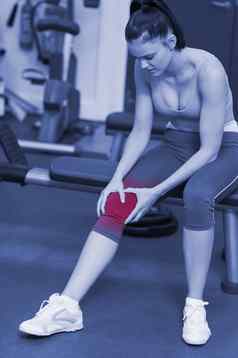 健康的女人受伤的膝盖坐着健身房