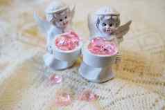 白色陶瓷小雕像天使持有篮子粉红色的心光背景