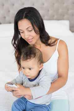 快乐浅黑肤色的女人持有婴儿智能手机