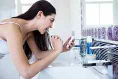 浅黑肤色的女人智能手机刷牙牙齿