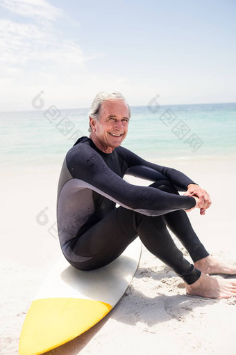 肖像快乐高级男人。潜水服坐着冲浪板