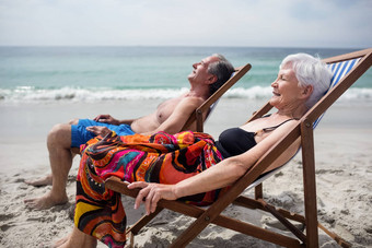 快乐高级夫妇放松躺椅海滩