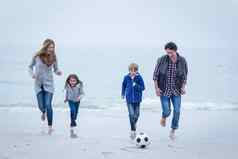 快乐的家庭玩足球海海岸天空