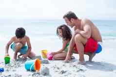 父亲帮助孩子们建筑沙子城堡海滩