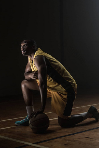 肖像篮球球员膝盖地板上手球