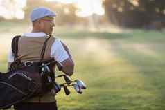后视图成熟的男人。携带高尔夫球袋