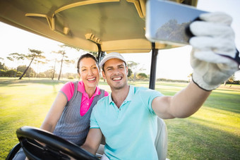 高尔夫球手夫妇采取自拍坐着高尔夫球车