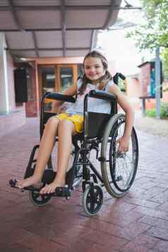 肖像可爱的女孩坐着轮椅走廊
