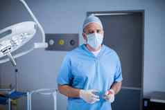 肖像外科医生持有外科手术工具操作房间